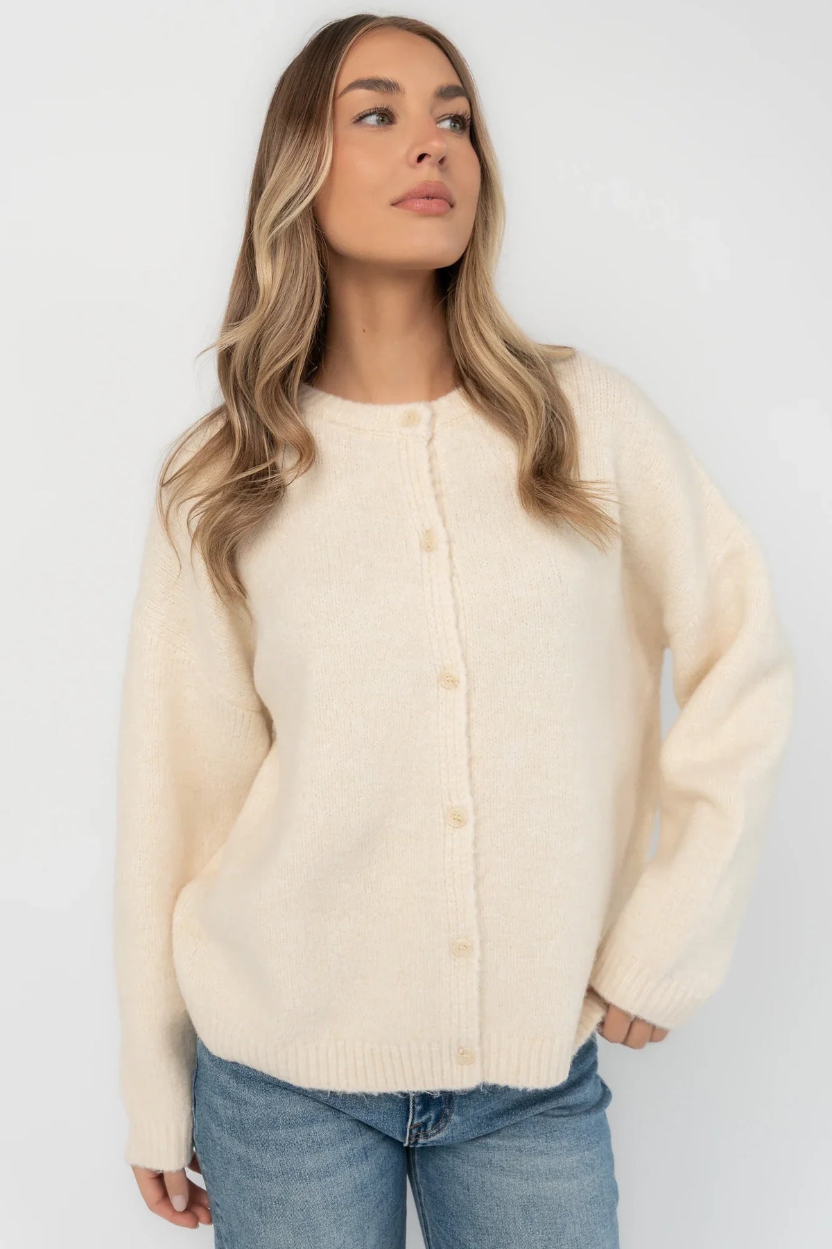 Cream fuzzy knit cardigan with a round neckline, button-front closure, long sleeves, dropped shoulders, and a relaxed fit.